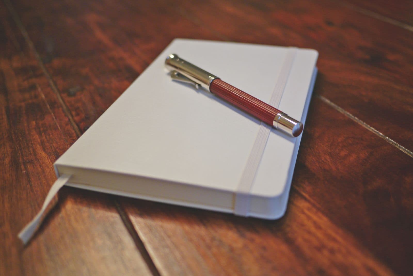 Nature morte éditoriale — carnet de cuir et stylo plume sur un bureau en bois